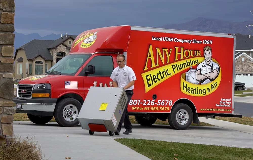 An Any Hour Services technician unloading equipment from a branded truck